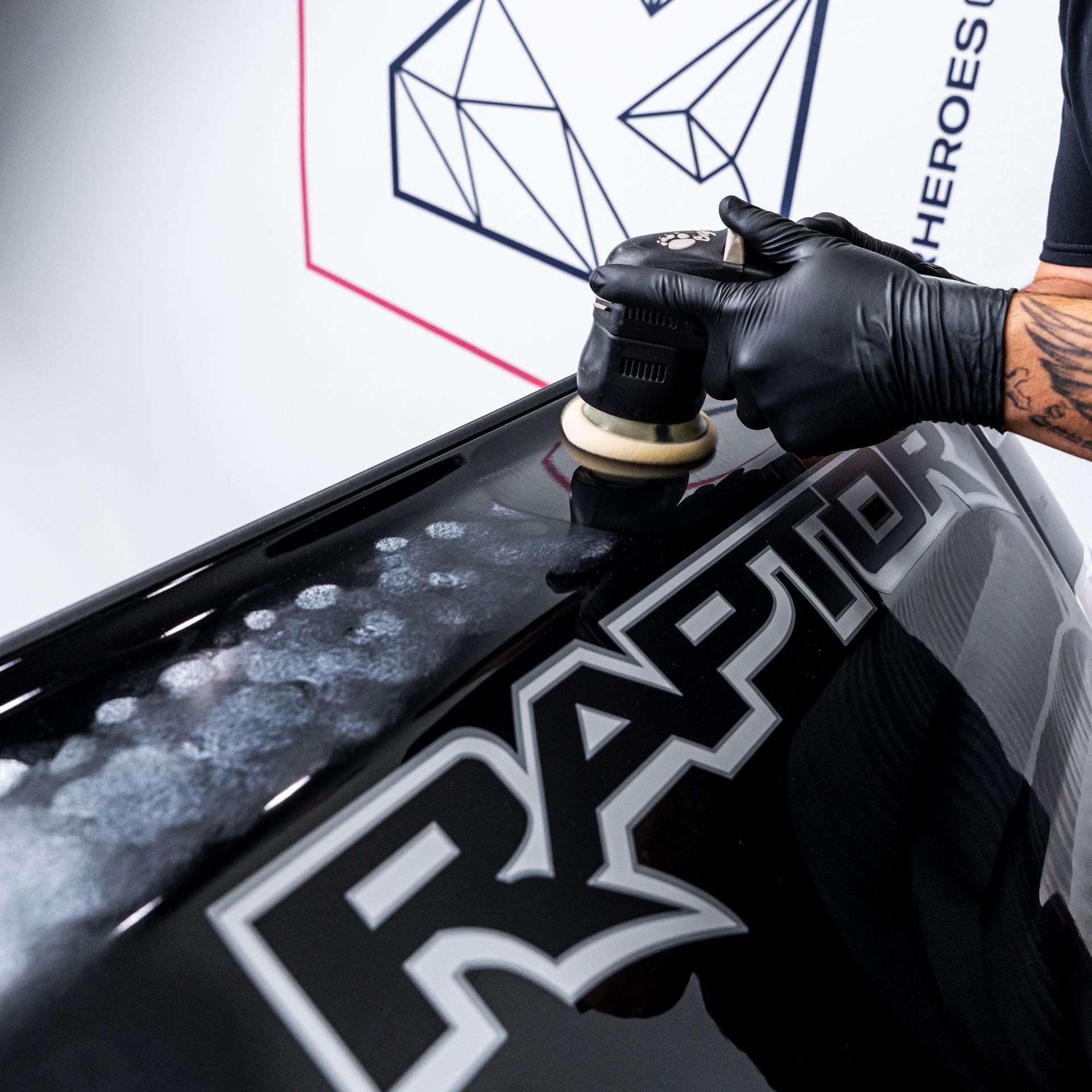Denver Auto Shield technician machine-polishing a black Ford Raptor hood during paint correction