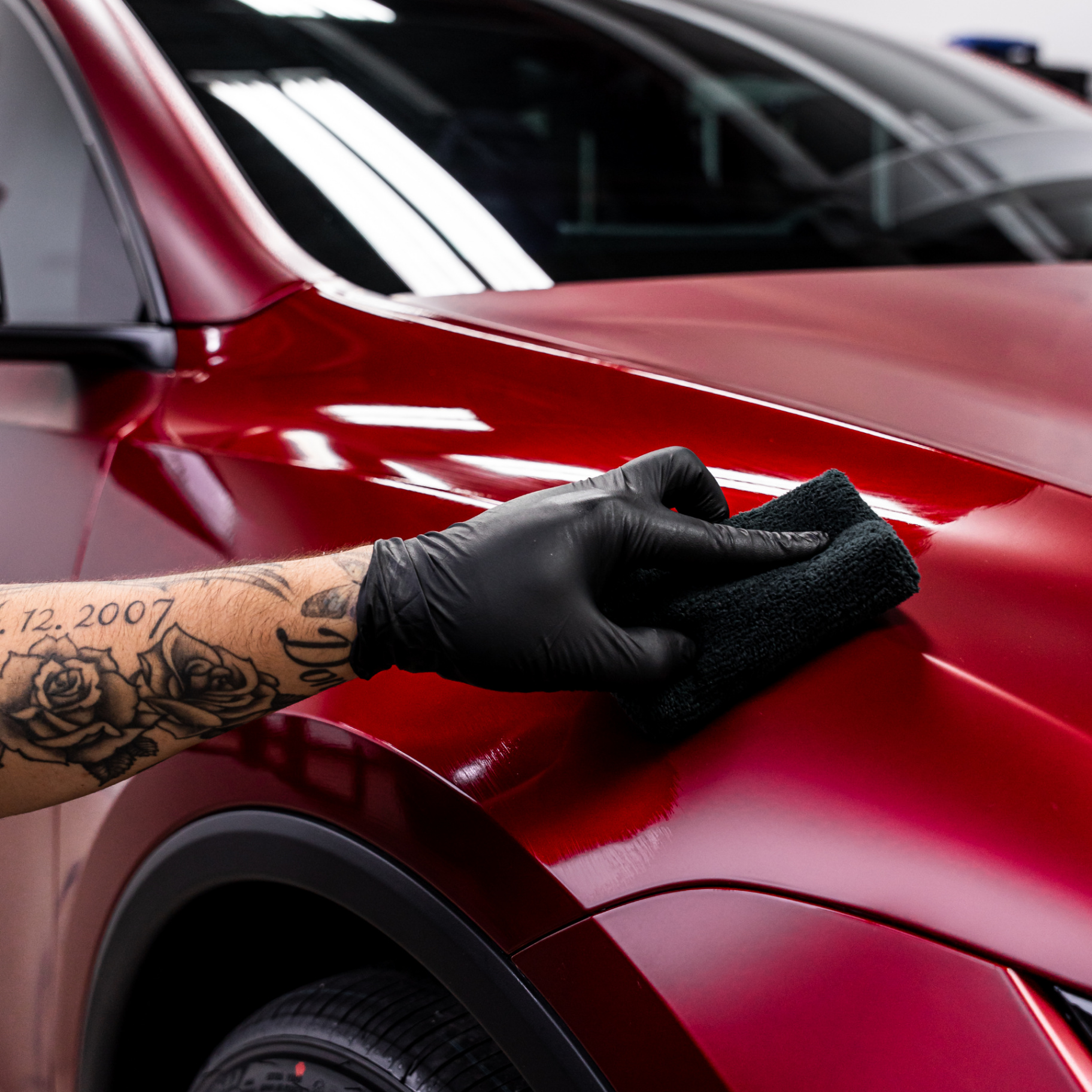 Technician leveling GYEON ceramic coating on a candy red vehicle fender at Denver Auto Shield